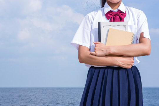 海辺でノートを抱く中学生