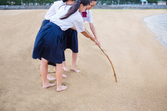 砂浜に文字を書く中学生