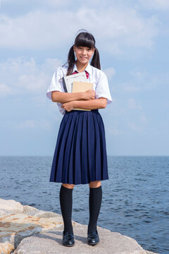 海辺でノートを抱く中学生