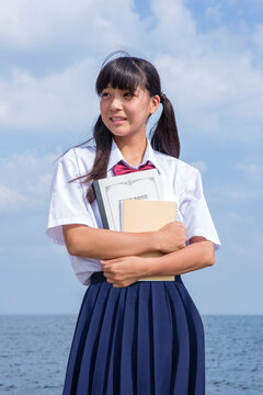 海辺でノートを抱く中学生