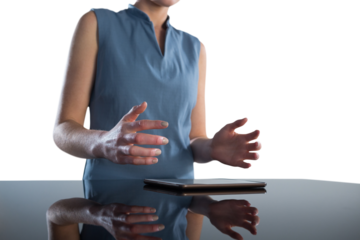 Mid section of businesswoman gesturing over digital tablet at table