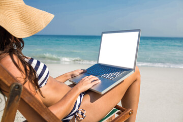 Pretty brunette using laptop on deck chair