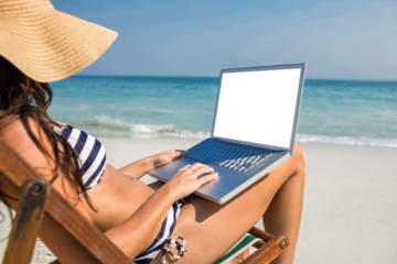 Pretty brunette using laptop on deck chair