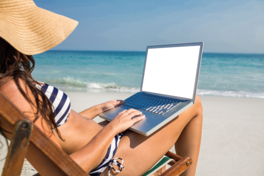 Pretty brunette using laptop on deck chair