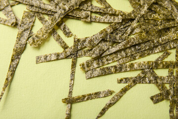 Cut nori sheets on green background, closeup