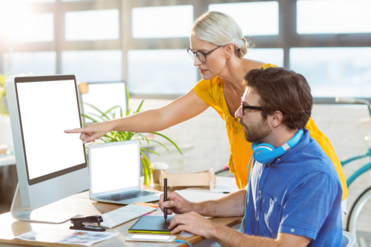 Graphic designers interacting while working on computer