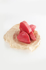 Pieces of raw tuna meat. Tuna pieces for steaks on craft paper. Isolated object. Photo on a white background.Isolated object.Copy space.Vertical photo.