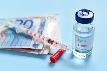 Insulin with syringe and money on blue background, closeup. Expensive medicine concept