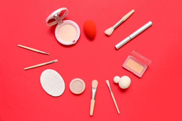 Frame made of decorative cosmetics with makeup brushes and sponges on red background