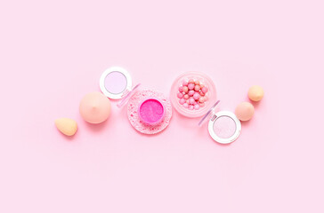 Decorative cosmetics with makeup sponges on pink background