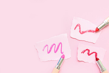 Lipsticks and papers with strokes on pink background