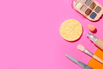 Decorative cosmetics with makeup brushes and sponges on color background