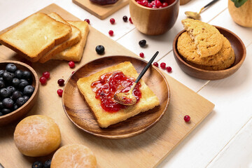 Plate of tasty toast with jam on light wooden background