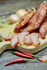 Dried or smoked sausage on a wooden table surrounded by spices and products. Meat production.