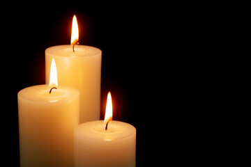 Fototapeta na wymiar Three white candles isolated on black background. Copy space for text.