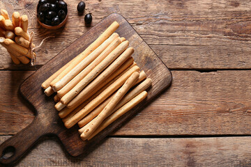 Board with tasty Italian Grissini on wooden background
