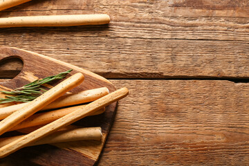 Board with tasty Italian Grissini on wooden background, closeup