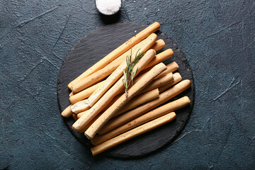 Slate board with tasty Italian Grissini on dark background