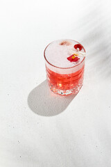 Aesthetic composition with alcoholic cocktail with flowers on white background. Pomegranate fizz in...