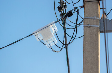An electric meter on a pole against a blue sky