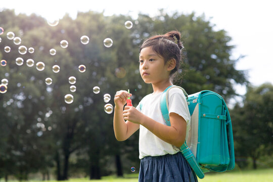 シャボン玉を飛ばして遊ぶ小学生の女の子