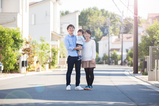 家の前の路上に立ち微笑む家族