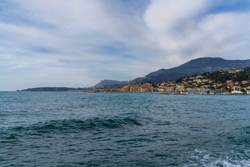 view of the colorful old city center of Menton with the blue Mediterranenan Sea in the foreground