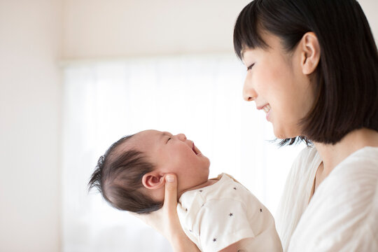 泣く赤ちゃんを抱いてあやす母親