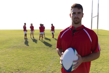 Rugby player holding football at field.