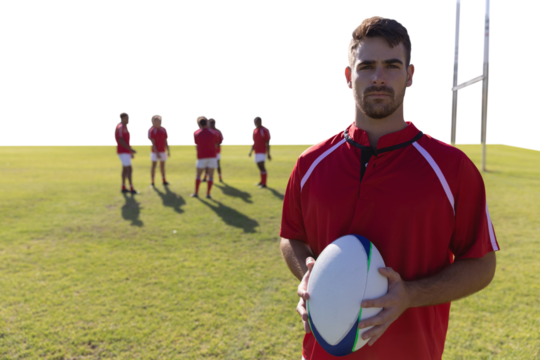 Rugby player holding football at field.