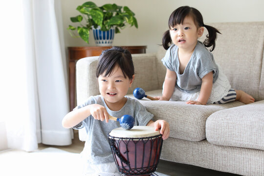 マラカスと太鼓で遊ぶ小さな姉妹