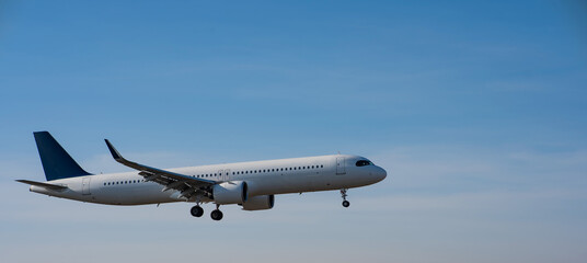 Fototapeta na wymiar Side view of an airplane landing against a blue sky. Widescreen. 