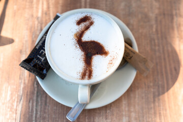 close-up view of a delicious coffee with milk and a Camargue flamingo in chocolate powder
