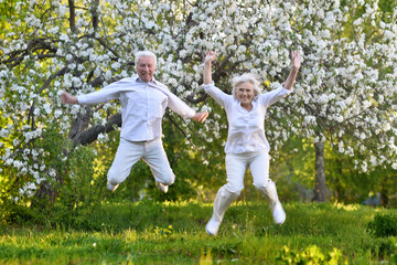 elderly couple jumps in summer in nature