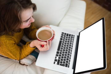 Smiling pretty woman using laptop while drinking coffee
