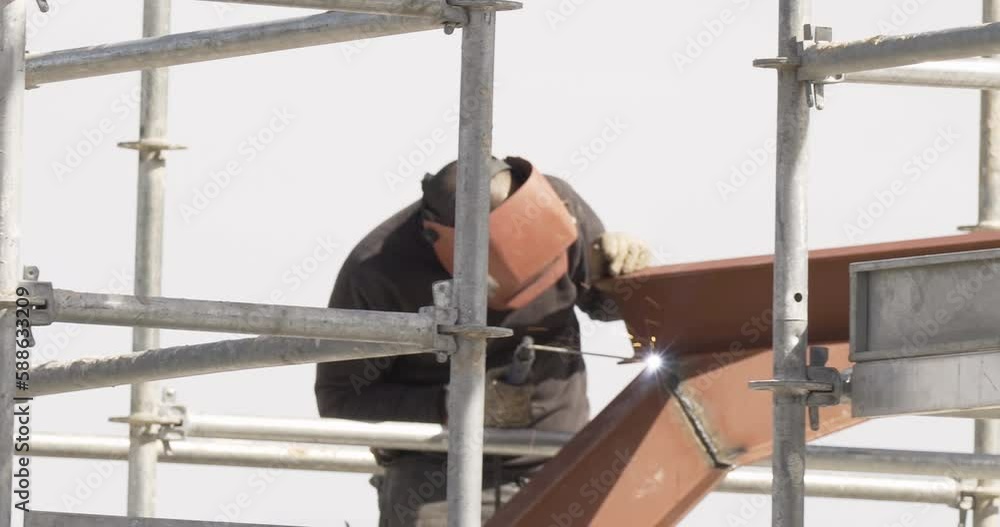 Poster detail of unrecognisable man welding roof structure scaffolding