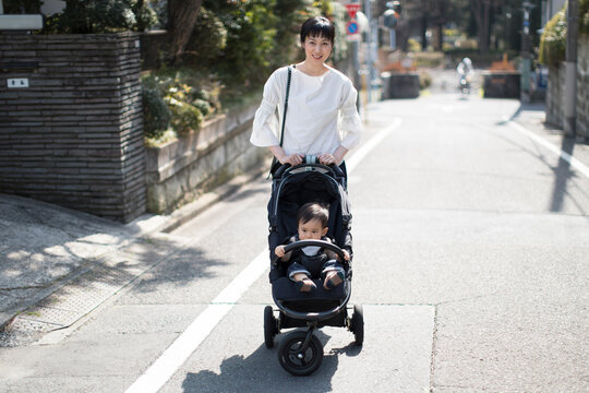ベビーカーに赤ちゃんを乗せて歩く母親