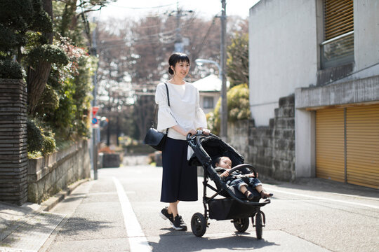 ベビーカーに赤ちゃんを乗せて歩く母親