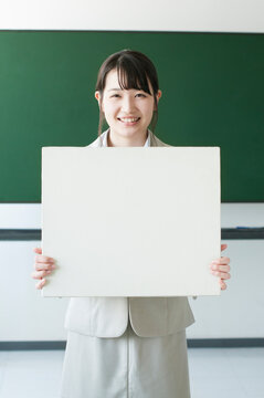 ホワイトボードを持ち微笑む先生