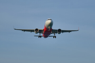 Airplane landing on blue sky background.
