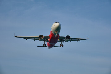 Airplane landing on blue sky background.