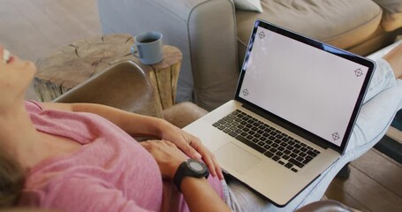 Happy caucasian pregnant woman sitting in armchair and using laptop with copy space