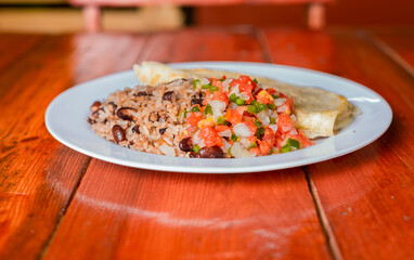Traditional Gallo Pinto Meal with Pico de Gallo and quesillo served, Gallopinto dish with quesillo and pico de gallo on wooden table