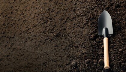 Dark earth with a black shovel / spade on the right side. Space for text. Ideal as background.