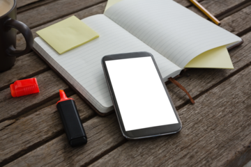 Organizer, coffee, mobile phone and stationery on wooden plank