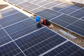 Portrait of latin hispanic engineer in safety helmet and uniform at solar power station installing solar panels. Green energy.