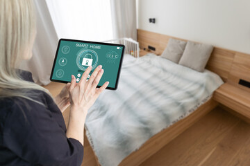 Side view pleasant young woman using smart home system or activating modern alarm system before leaving apartment. Happy lady turning off easy security technology, when returning house or flat