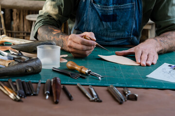 Close-up hand being picked up selection handcrafted leathercraft tools every step way, hand mechanic picks up variety equipment, wanted use from many placed equipment, skillfully handcrafted.