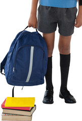Schoolboy holding bag while standing by books over white background