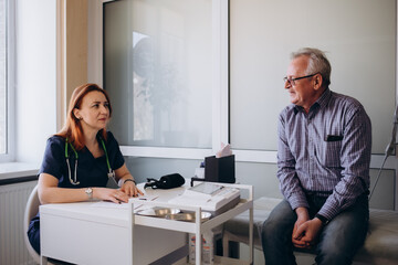 Close up caring nurse holding smiling mature patient hand at meeting in hospital, doctor caregiver...